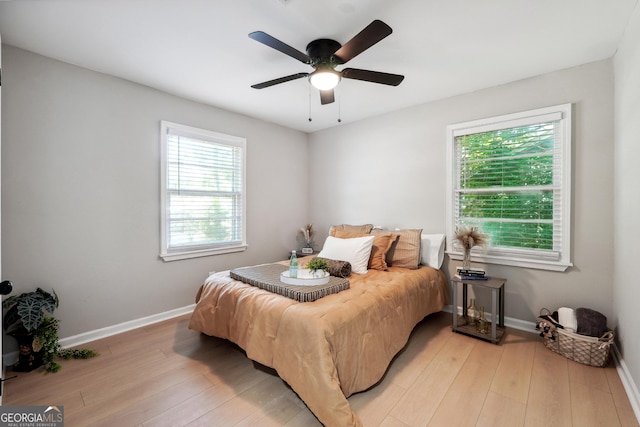 bedroom with a ceiling fan, baseboards, multiple windows, and light wood finished floors