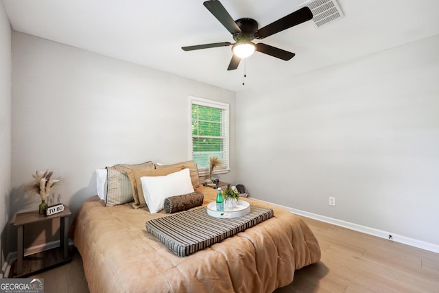 bedroom with a ceiling fan, baseboards, visible vents, and wood finished floors