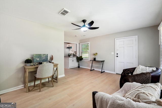 living room with a ceiling fan, baseboards, visible vents, and light wood finished floors