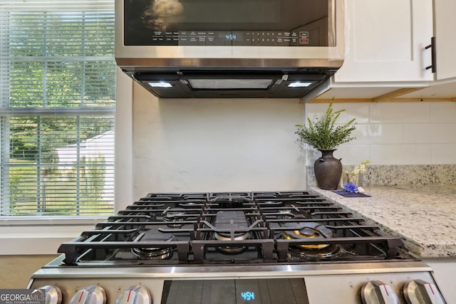 785 Alice St, Forest Park, GA 30297 - interior details with light stone countertops, gas range, range hood, white cabinetry, and tasteful backsplash