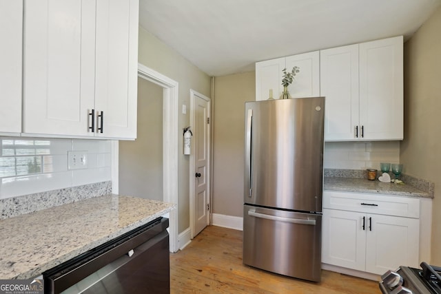 785 Alice St, Forest Park, GA 30297 - kitchen with tasteful backsplash, light stone counters, light wood-style floors, stainless steel appliances, and white cabinetry