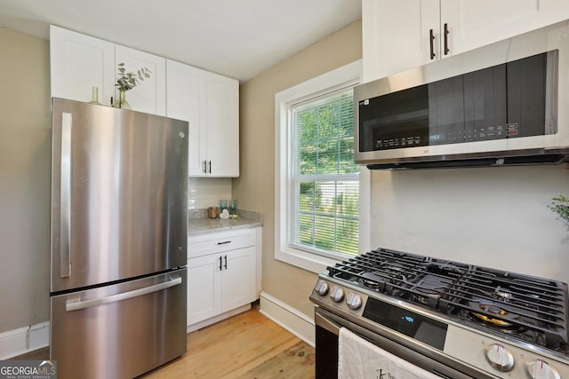 785 Alice St, Forest Park, GA 30297 - kitchen with light stone countertops, baseboards, white cabinets, light wood finished floors, and stainless steel appliances