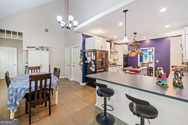 kitchen with appliances with stainless steel finishes, wood finished floors, white cabinets, a peninsula, and a chandelier