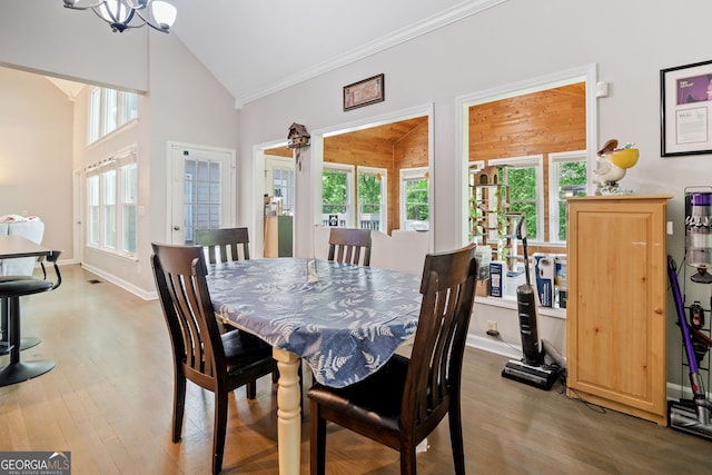 dining space featuring crown molding, wood finished floors, high vaulted ceiling, baseboards, and a chandelier