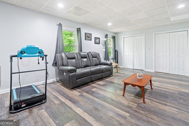 living area with a paneled ceiling, baseboards, and wood finished floors
