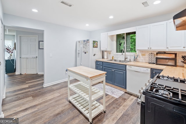 kitchen with blue cabinets, visible vents, a sink, white cabinets, and white appliances