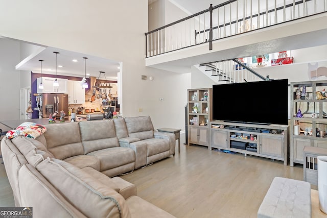 living area with stairway, a high ceiling, and light wood finished floors