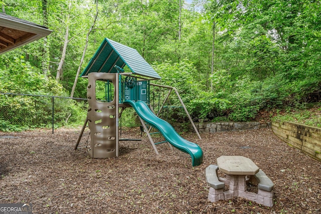 communal playground featuring fence and a forest view