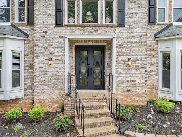 view of exterior entry featuring brick siding and french doors