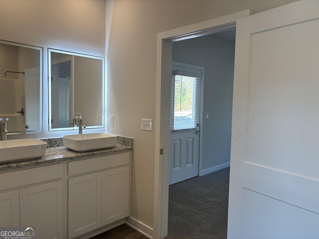 bathroom featuring double vanity, baseboards, and a sink