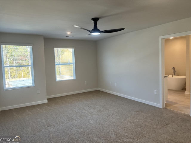 carpeted spare room featuring baseboards and ceiling fan