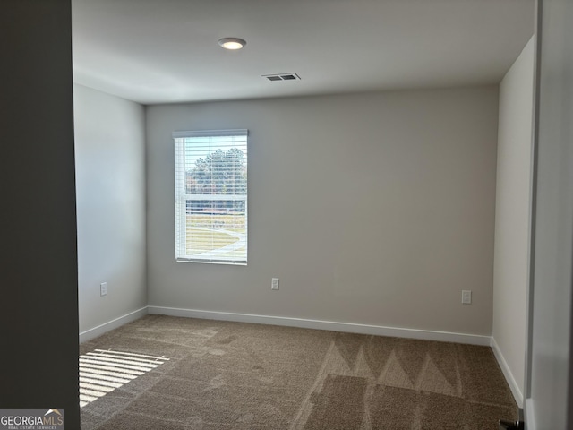 empty room featuring visible vents, baseboards, and carpet floors