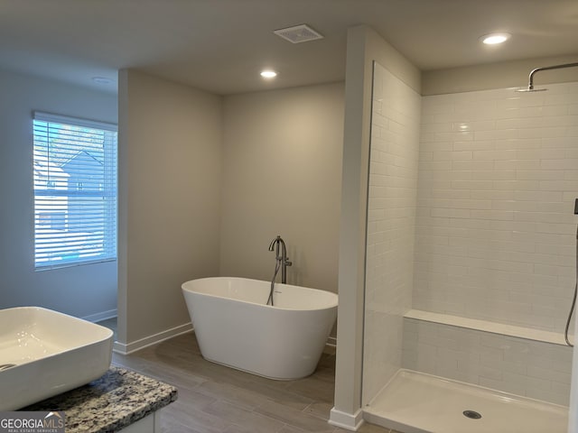 full bathroom featuring a shower stall, a freestanding bath, plenty of natural light, and wood finished floors