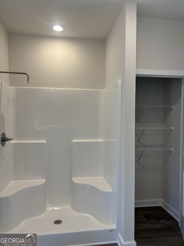 bathroom with wood finished floors, recessed lighting, baseboards, and a shower