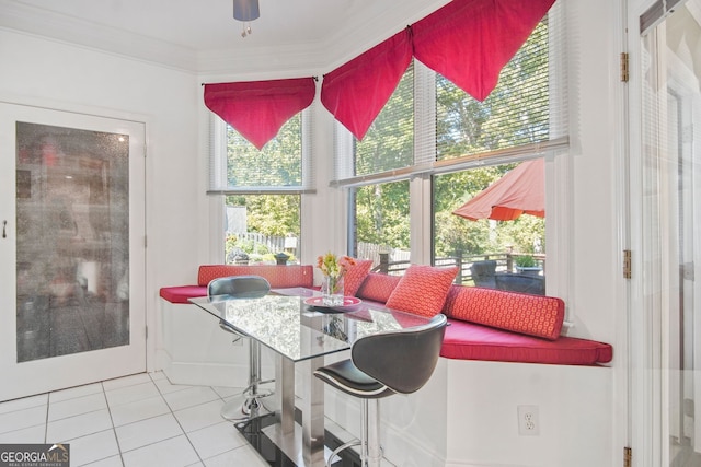 tiled dining space featuring ornamental molding and a ceiling fan