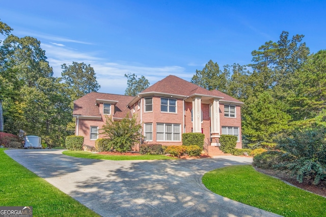 view of front facade with curved driveway, a front yard, and brick siding