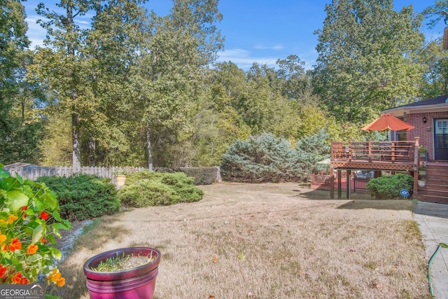 view of yard featuring a deck, fence, and stairs