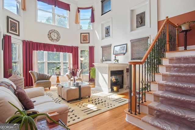 living room featuring a healthy amount of sunlight, stairs, wood finished floors, and a towering ceiling