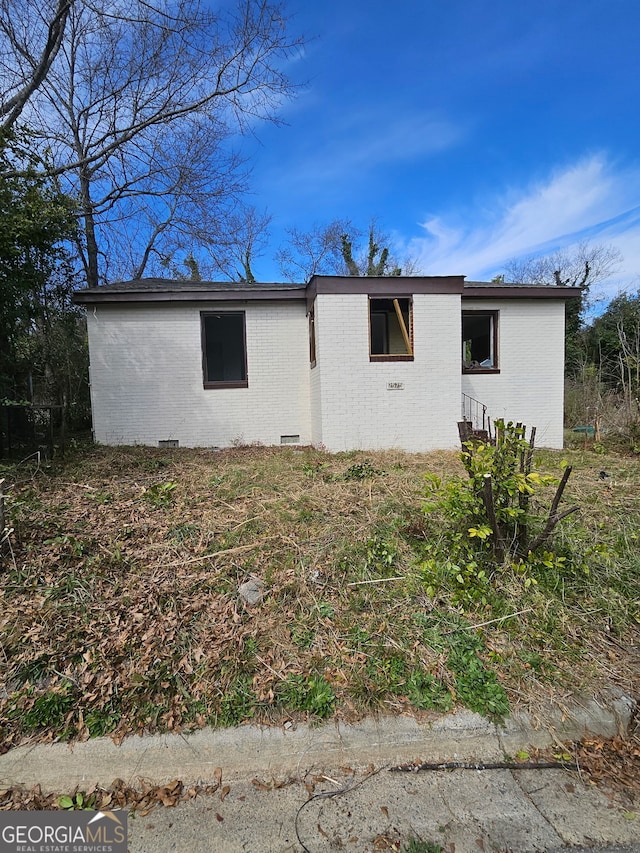 view of side of property featuring brick siding and crawl space