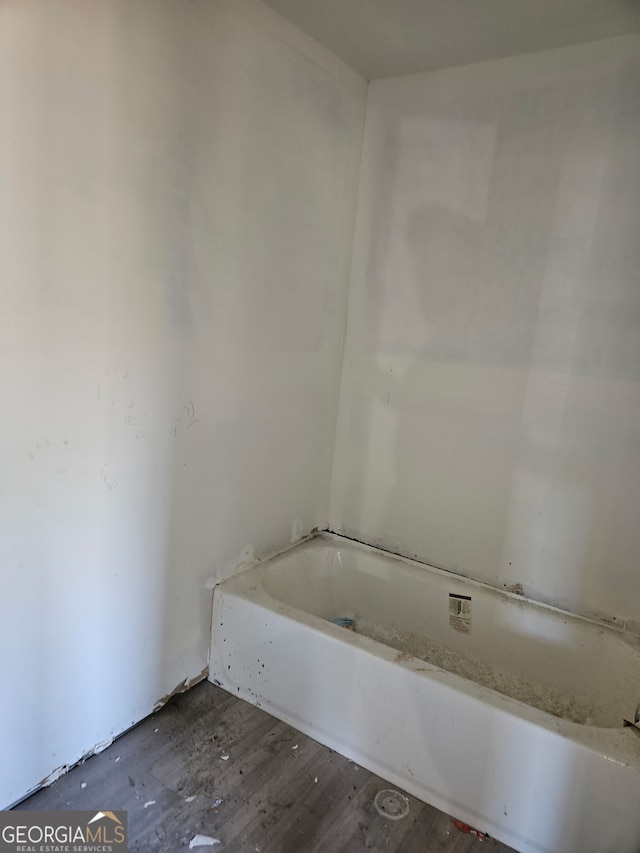 bathroom featuring wood finished floors and a bath