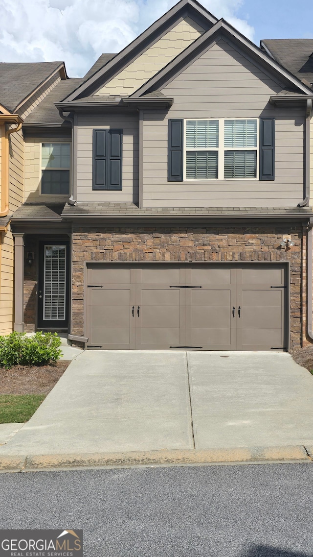 view of front facade with driveway, stone siding, and a garage