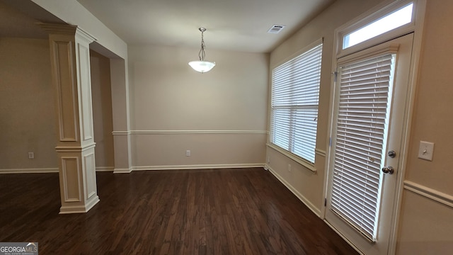 unfurnished dining area with ornate columns, dark wood-style floors, and visible vents