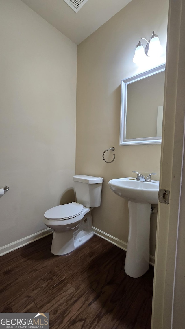 bathroom with baseboards, a sink, wood finished floors, and toilet
