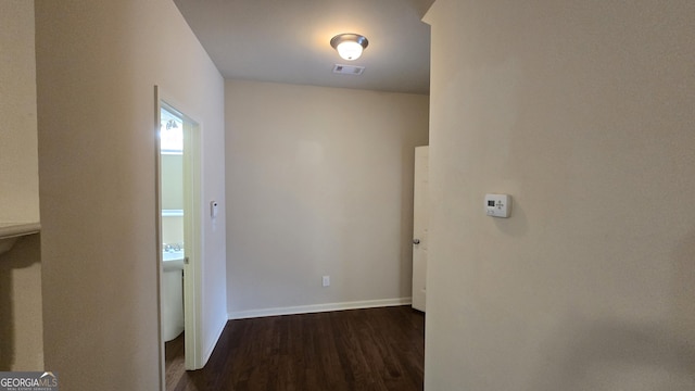 hall with dark wood-type flooring, baseboards, and visible vents