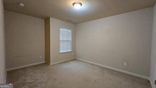 carpeted empty room featuring baseboards and visible vents