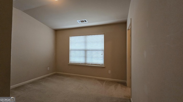 carpeted empty room with baseboards, vaulted ceiling, and visible vents