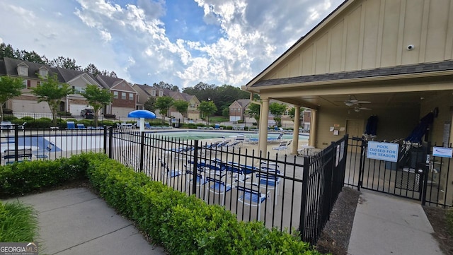 pool with a ceiling fan, fence, and a residential view