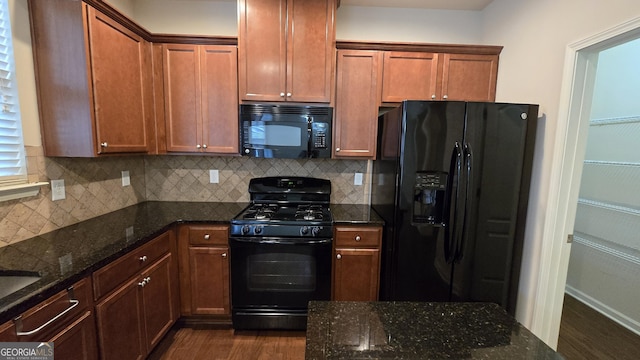 kitchen featuring decorative backsplash, black appliances, dark wood finished floors, and dark stone countertops