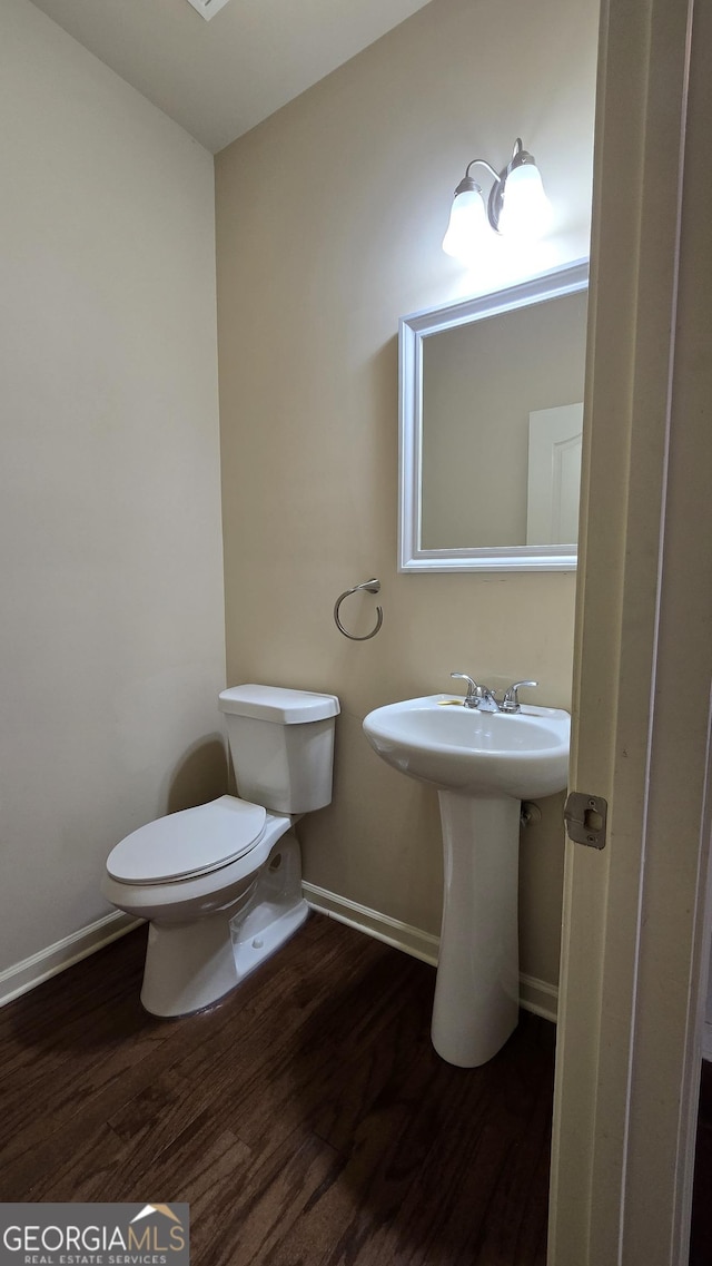 half bathroom featuring toilet, baseboards, and wood finished floors