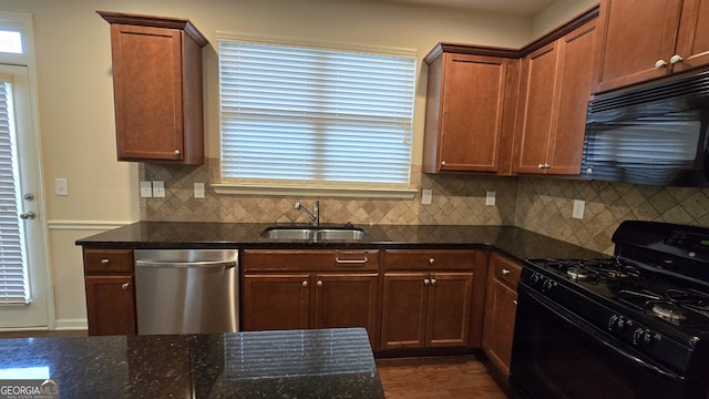 kitchen featuring a sink, dark stone counters, tasteful backsplash, and black appliances
