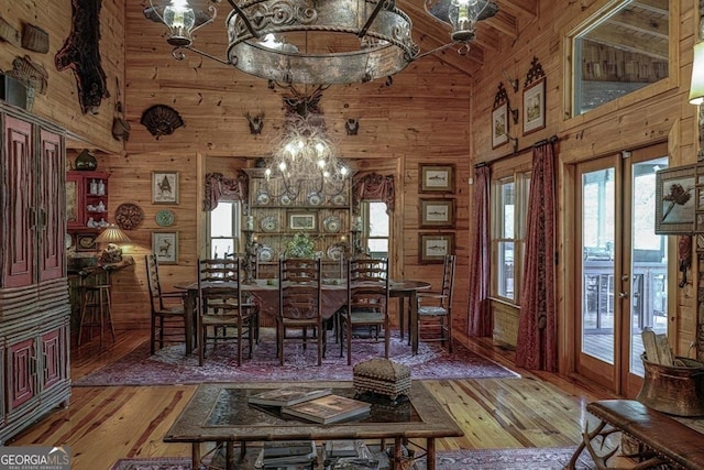 dining space featuring high vaulted ceiling, wood walls, plenty of natural light, and light wood finished floors