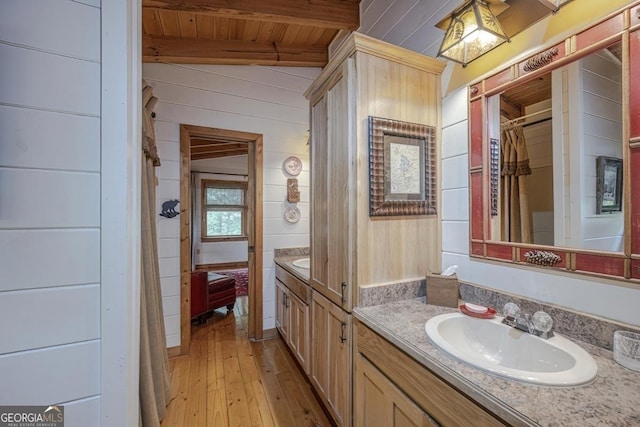full bath with hardwood / wood-style flooring, wooden ceiling, vanity, beamed ceiling, and wooden walls