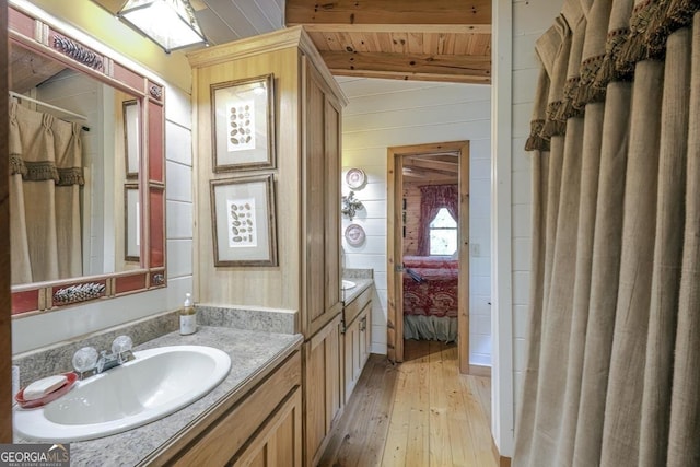 full bathroom featuring connected bathroom, wooden walls, vanity, hardwood / wood-style floors, and wooden ceiling