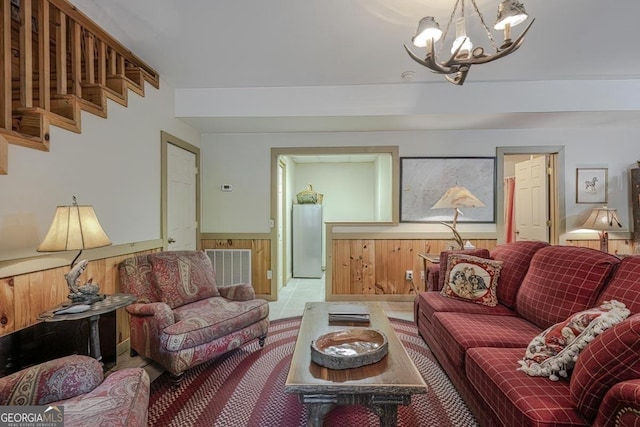 living area featuring visible vents, a wainscoted wall, and a chandelier