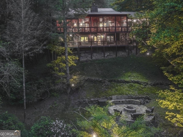 view of yard with a wooden deck, a sunroom, and an outdoor fire pit
