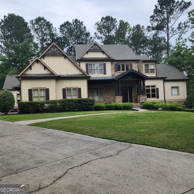 craftsman-style house featuring a standing seam roof, stone siding, roof with shingles, and a front yard