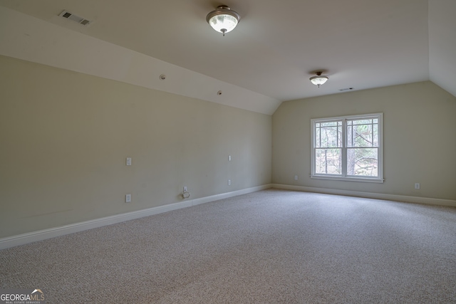 spare room with vaulted ceiling, visible vents, baseboards, and carpet floors