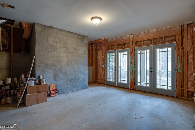 spare room featuring unfinished concrete flooring and french doors