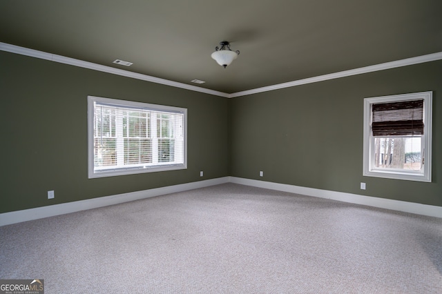 carpeted empty room featuring baseboards, ornamental molding, and visible vents