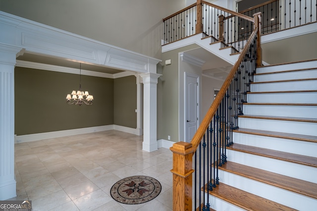 stairs with a notable chandelier, tile patterned floors, baseboards, decorative columns, and a towering ceiling