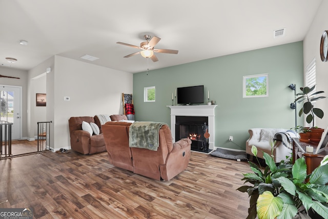 living area featuring visible vents, ceiling fan, wood finished floors, and a healthy amount of sunlight