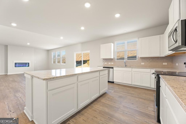 kitchen featuring a healthy amount of sunlight, a center island, tasteful backsplash, a sink, and stainless steel appliances