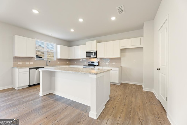 kitchen featuring white cabinets, tasteful backsplash, a kitchen island, and stainless steel appliances