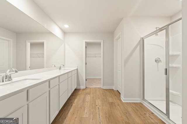 bathroom with a sink, baseboards, a shower stall, and wood finished floors