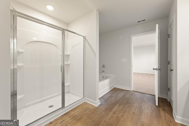 full bathroom with a garden tub, visible vents, a shower stall, wood finished floors, and baseboards