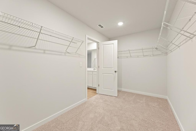 spacious closet with visible vents and light colored carpet
